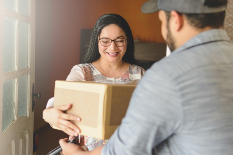 Woman receiving a package at home from delivery man