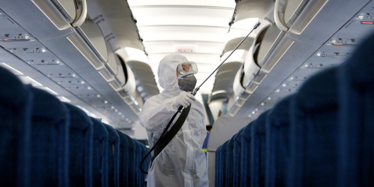 A health worker sprays disinfectant inside a Vietnam Airlines plane in Hanoi on Feb. 21, 2020.
