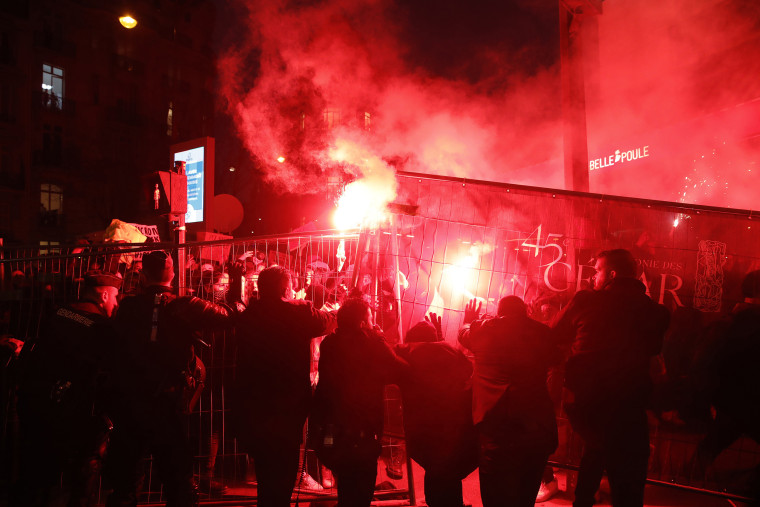 People demonstrate behind a security fence outside the venue of the Cesar awards ceremony, the French equivalent of the Oscars.