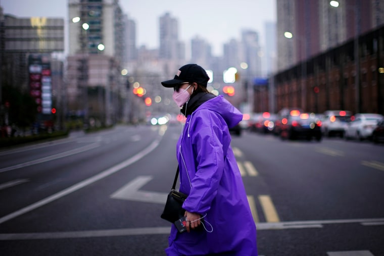 Image: A woman wearing a protective mask crosses a street in Shanghai on Feb. 26, 2020.