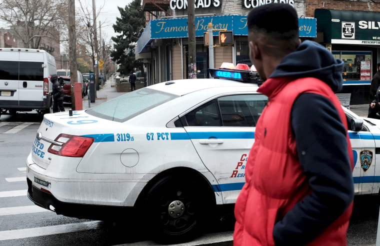 People walk past a police car in the in the Brownsville neighborhood of Brooklyn on Nov. 18, 2019 in New York.