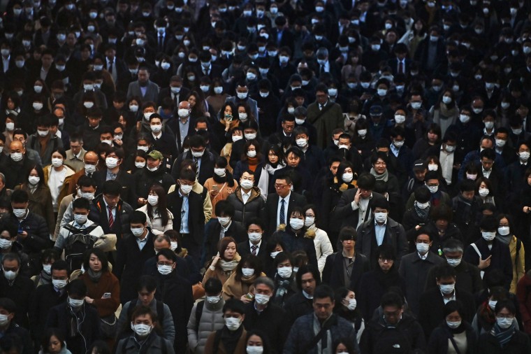 Mask-clad commuters make their way to work during morning rush hour at the Shinagawa train station in Tokyo on Feb. 28, 2020.