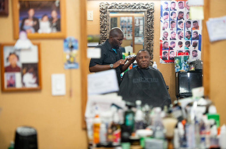 Image: Barber Anderson J. Washington with veteran Charles Peaks at CJ's Barbershop.