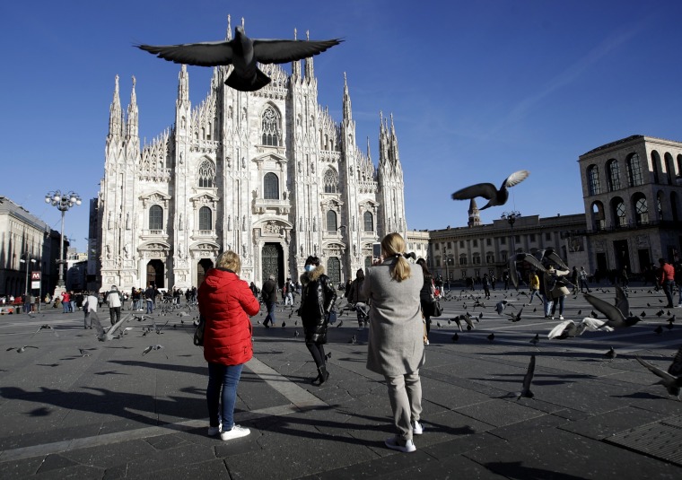 Image: A woman wearing a protective mask poses outside the Duomo in Milan on Feb. 28, 2020.