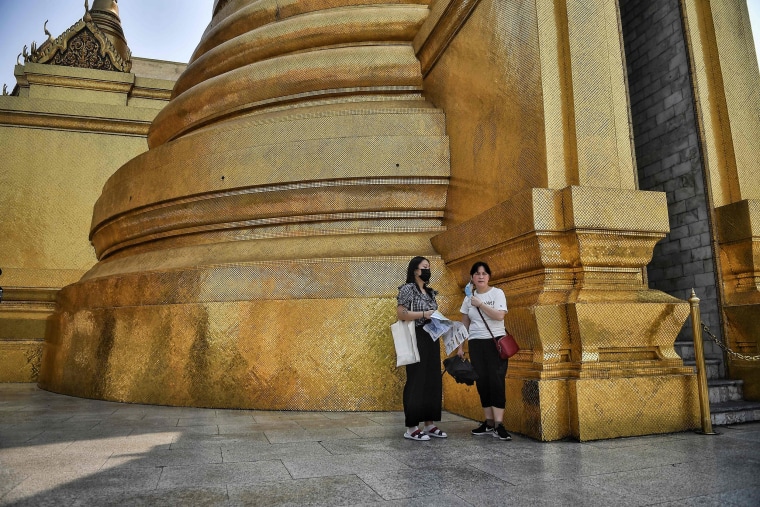 Image: Tourists, wearing facemasks amid concerns over the spread of the COVID-19 novel coronavirus, walk through an unusually empty Grand Palace in Bangkok