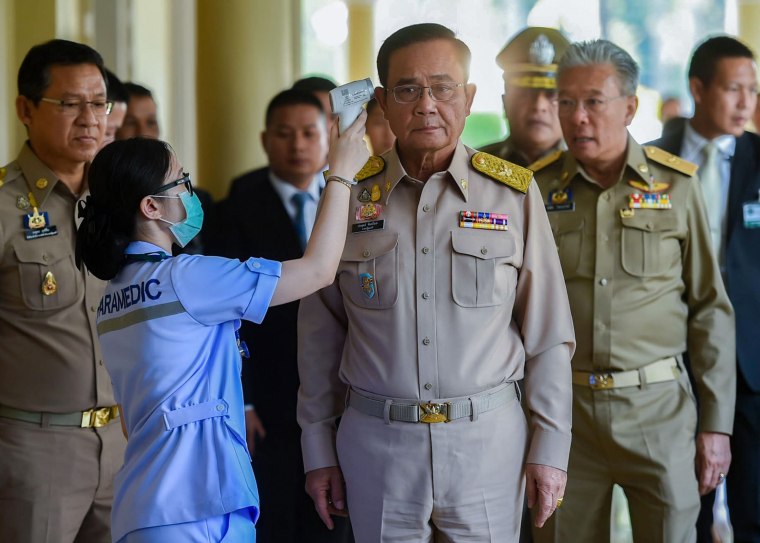 A paramedic checks the temperature of Thailand's Prime Minister Prayuth Chan-ocha