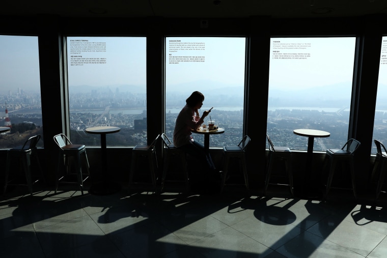 Image: A woman sits at an empty cafe in Seoul, South Korea on Monday.