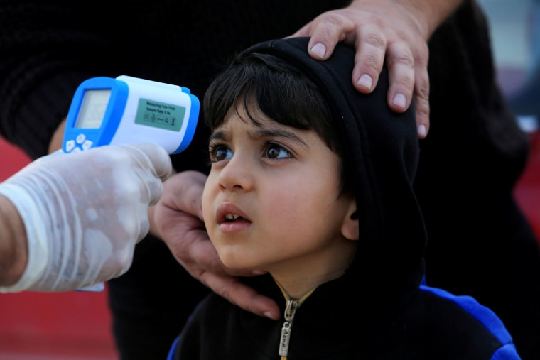 Image: A member of the medical team checks the temperature of a child, following the coronavirus outbreak, at a checkpoint on the outskirts of Duhok, Iraq