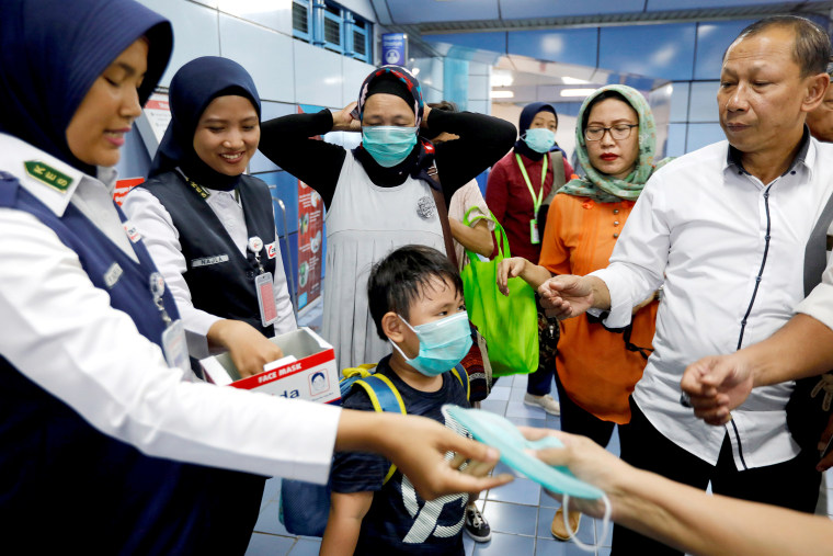 Image: Indonesia's commuter train officials distribute free-protective masks to the passengers following confirmed cases of the novel coronavirus disease of COVID-19 in Jakarta