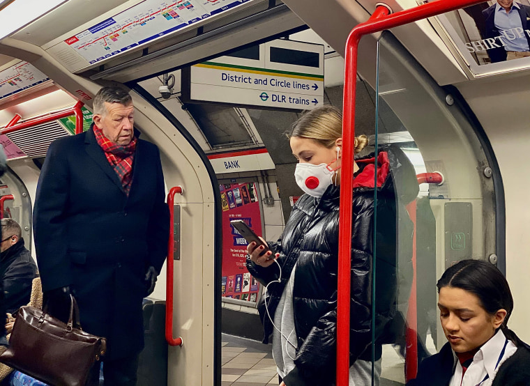 Image: A woman wears a protective face mask as she travels on a London tube train carriage at Bank Underground station in central London