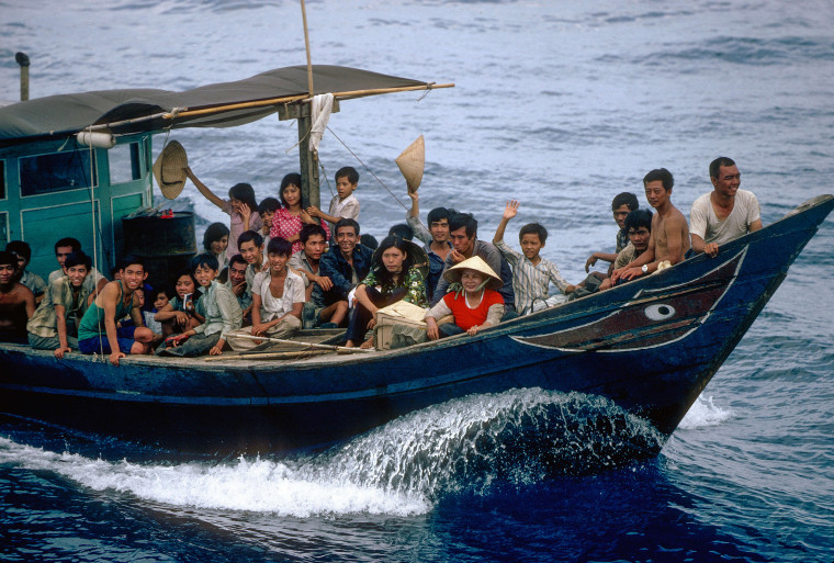Vietnamese refugees on a boat approach a rescue ship