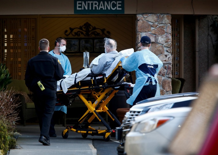 Image: Medics wheel out a person on a stretcher from the Life Care Center of Kirkland