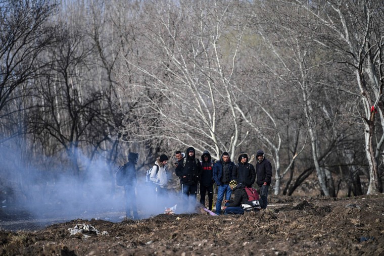 Image: Migrants keep warm as they gather near the Tunca river waiting to resume their efforts to enter Europe in Edirne