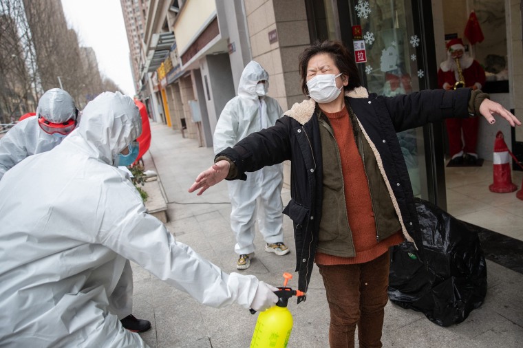 Image: A woman, who has recovered from the COVID-19 coronavirus infection, is disinfected by volunteers as she arrives at a hotel for a 14-day quarantine after being discharged from a hospital in Wuhan, in China's central Hubei province