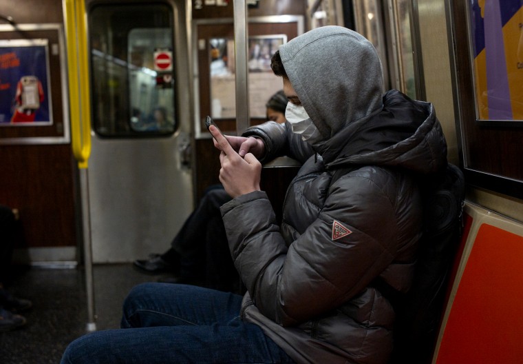 Image: A man wearing a face mask reads his phone on the subway in New York on Feb. 2, 2020.