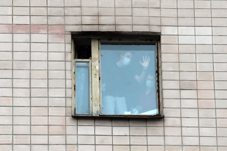 Image: People wearing face masks in the window of a quarantined building housing the dormitory of the North-Western State Medical University named after I.I. Mechnikov in Saint Petersburg