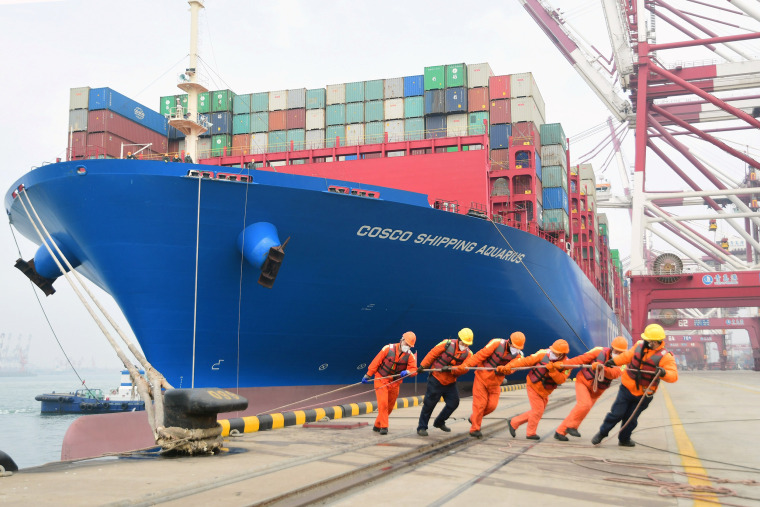 Image: Workers wearing face masks rope a container ship at a port in Qingdao