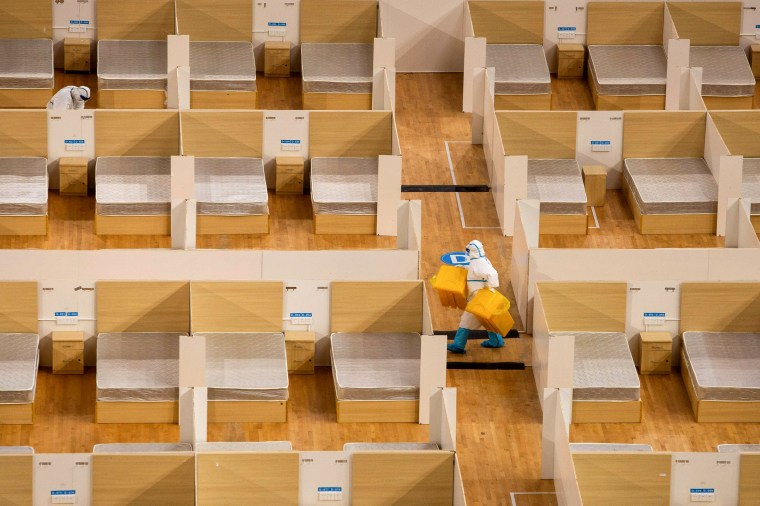 Image: A staff member removes waste after the final patients were discharged from a temporary hospital set up to treat people diagnosed with coronavirus in a sports stadium in Wuhan, China, on March 8, 2020.