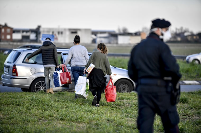 Image: People carry supplies while waiting to enter the formerly quarantined town of Casalpusterlengo in the Lombardy region of Italy on March 8, 2020.