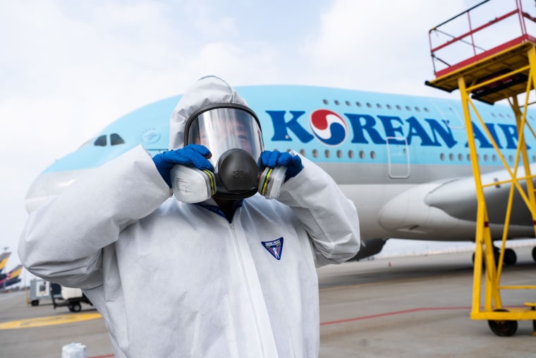 Image: A worker checking his protective gear as he prepares to spray disinfectant on an airplane as part of preventive measures against the spread of the COVID-19 coronavirus, at Incheon International Airport in South Korea