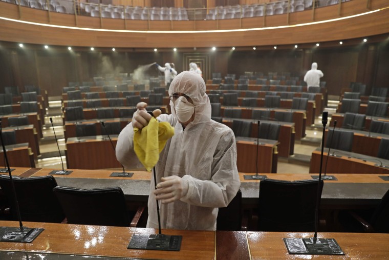 Workers disinfect the desks and chairs of the Lebanese Parliament in central Beirut on March 10, 2020.