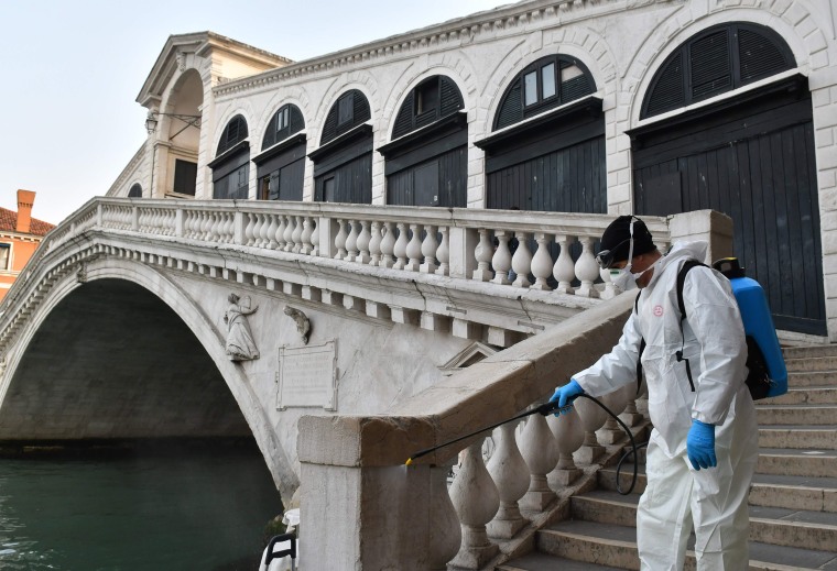 Image: An employee of the municipal company Veritas sprays disinfectant in public areas at the Rialto Bridge in Venice