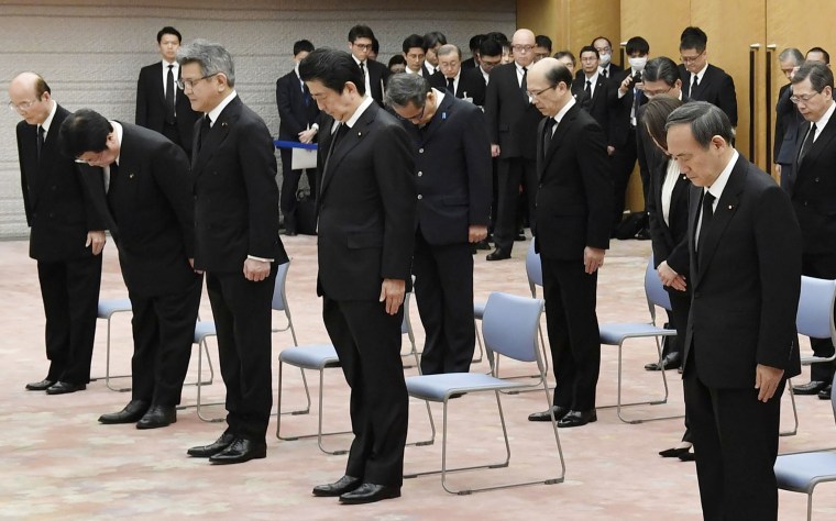 Image:Japanese Prime Minister Shinzo Abe, center, observes a moment of silence to mark the moment nine years ago a magnitude 9.0 earthquake struck off Japan's coast, triggering a devastating tsunami and nuclear disaster.