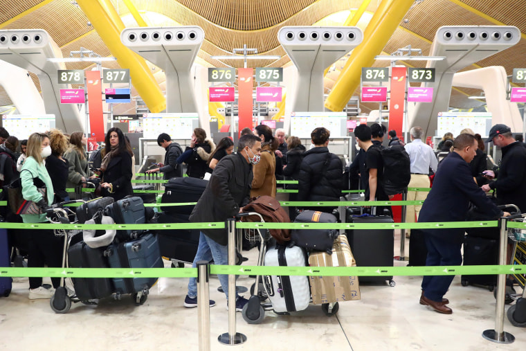 Image: Passengers, wearing protective face masks, wait for checking-in before boarding their flights to the U.S. at Madrid's Adolfo Suarez Barajas airport