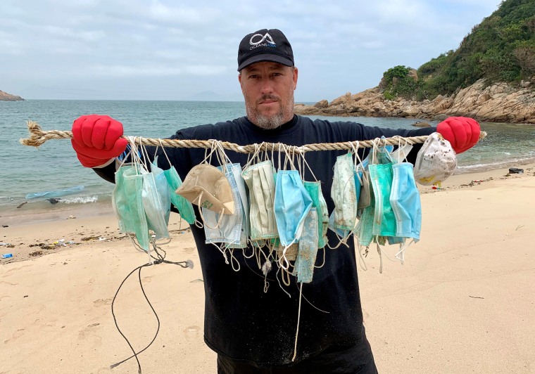 Image: Gary Stokes, co-founder of marine conservation group OceansAsia, shows face masks that washed up on the beach of Soko Islands, following an outbreak of the novel coronavirus, in Hong Kong
