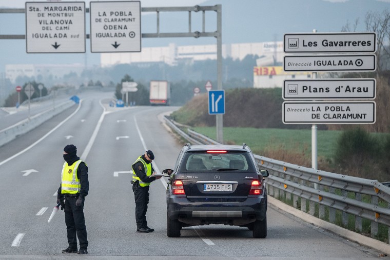 Image: A Catalan Police officer, Mossos d'Escuadra register a car trying to arrive to Igualada at a check-point outside the city on March 13, 2020 near Barcelona, Spain.