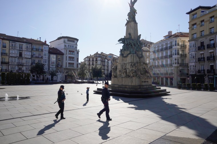 Image: Police officers cross a virtually deserted square, amidst concerns over Spain's coronavirus outbreak, in the Basque city of Vitoria,