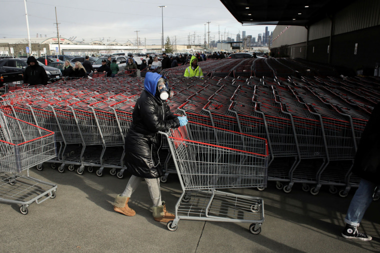 Image: Dee Jackson wears a gas mask as she and other shoppers line up before opening at a Costco store, following reports of coronavirus disease (COVID-19) cases in the country, in Seattle