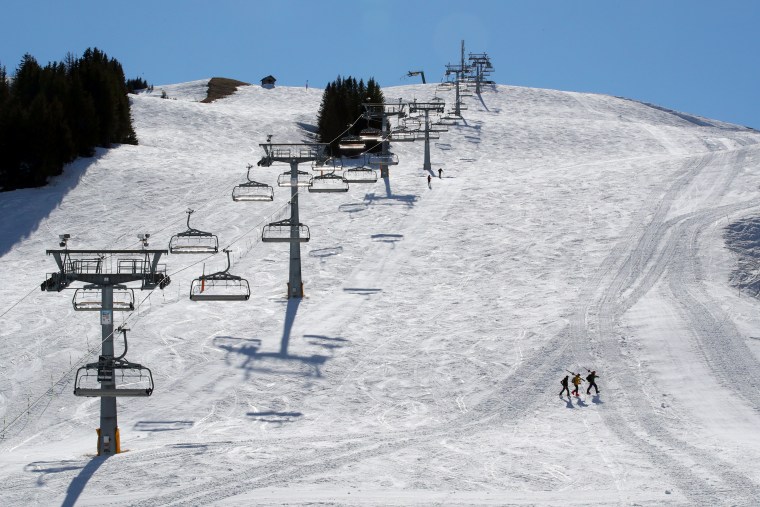 Image: Skiers walk past a closed chair-lift in Les Crosets