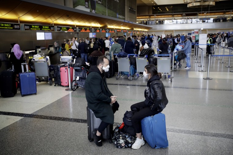 Image: People wait to check in their luggage at Los Angeles International Airport on March 14, 2020.
