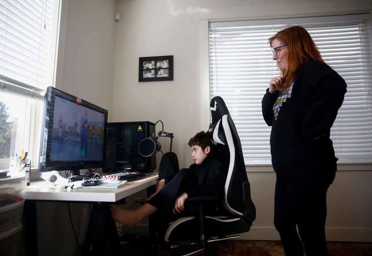 Image: Pucci and son Harding, 12, watch an exercise video created by Foxton's teachers at Northshore Middle School as the school district moves to online learning for two weeks due to coronavirus concerns, photographed at their home in Bothell