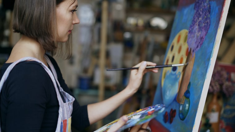 Young artist woman painting still life picture on canvas in art-school