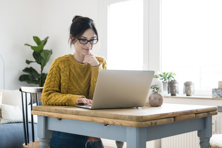 Woman sitting at table, using laptop