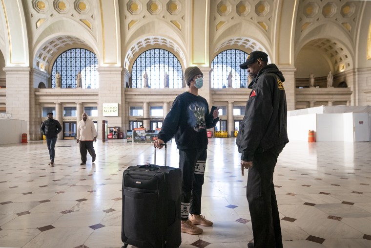 A traveler talks with a security officer at Washington Union Station, a major transportation hub in the nation's capital, on March 16, 2020.