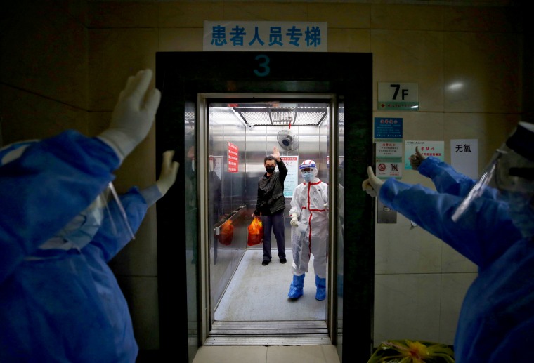 Image: Medical staff wave goodbye to a patient who recovered from coronavirus at the Red Cross Hospital in Wuhan, China, on March 16, 2020.