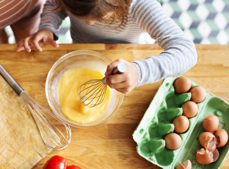 Young girl whipping eggs in a bow