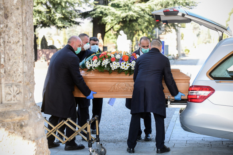 Undertakers carry a coffin out of a hearse on March 16, 2020 at the Monumental cemetery of Bergamo, Italy, as burials of coronavirus victims are conducted approximately every half hour.