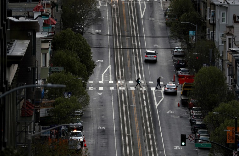 Two pedestrians cross an empty San Francisco street on Monday.