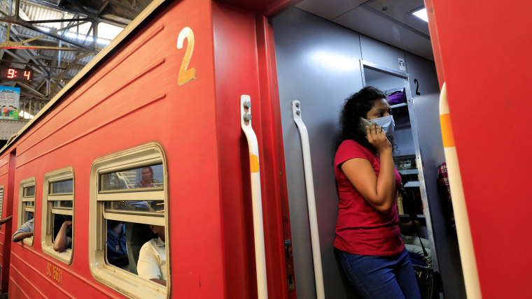 Image: A woman wearing a protective mask speaks over a phone as she stands inside a train at Fort railway station, as the number of people tested positive for coronavirus disease (COVID-19) in the country increased, in Colombo, Sri Lanka,