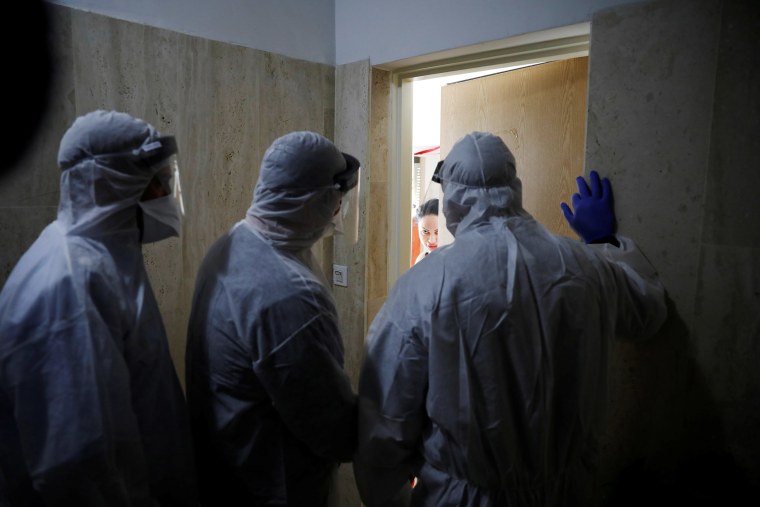 Image: Health Ministry inspectors speak with a woman who is in self quarantine as a precaution against coronavirus spread in Hadera