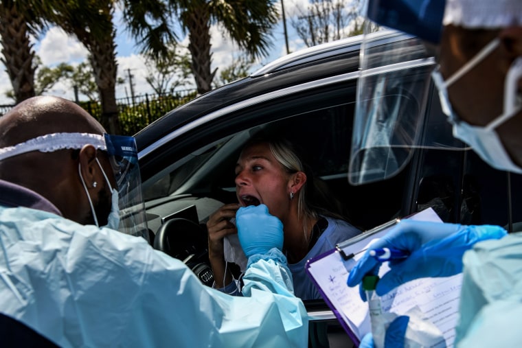 Image: A medical personnel member takes samples of Lee Dinzik at a "drive-thru" coronavirus testing lab set up by a local community center in West Palm Beach