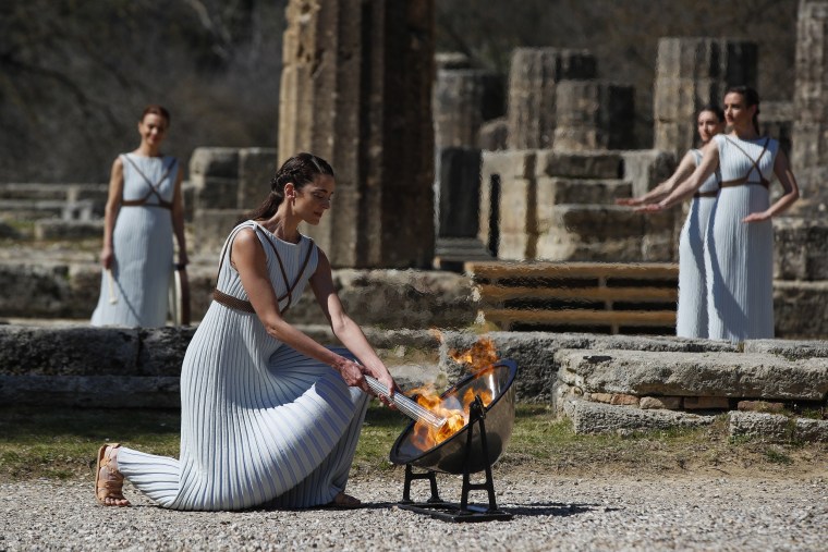 Image: Greek actress Xanthi Georgiou, playing the role of the High Priestess, lights up the torch during the flame lighting ceremony at the closed Ancient Olympia site, birthplace of the ancient Olympics in southern Greece
