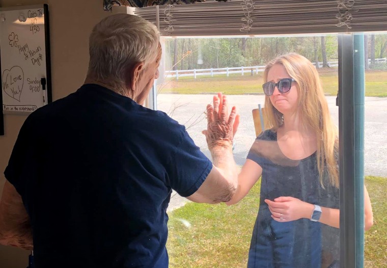 Image: Carly Boyd and her grandfather, Shelton, speak through a window at the locked down Premier Living and Rehab Center in North Carolina.