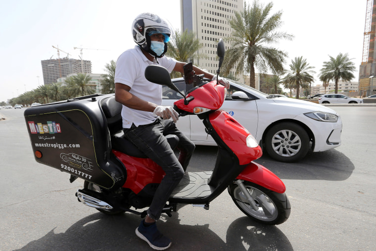 Image: A delivery man rides to deliver food, as restaurants closed, following the outbreak of coronavirus in Riyadh, Saudi Arabia.