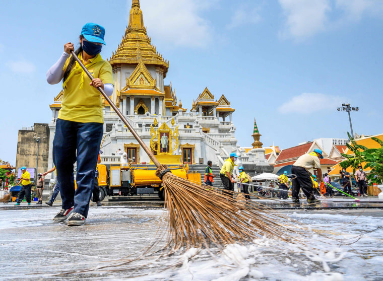 Image: Volunteers use disinfectant to clean Wat Traimit temple in Bangkok on March 18, 2020, amid concerns over the spread of coronavirus.