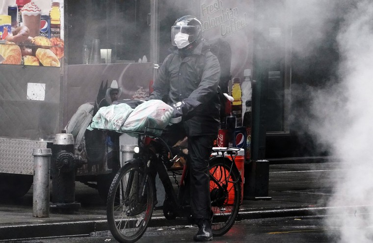 Image: A delivery person on a bike rides though a steam cloud in Times Square following the outbreak of Coronavirus disease (COVID-19), in the Manhattan borough of New York City